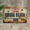 Rusted metal wall sign reading Omaha Beach 8KM with route marker D514