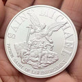 Saint Michael challenge coin, silver, held in hand
